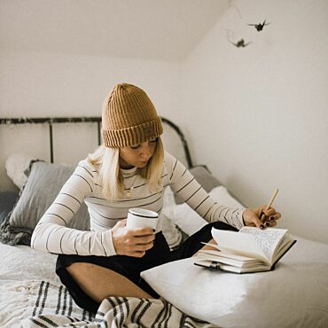 A student is sitting on her bed in a student residence.