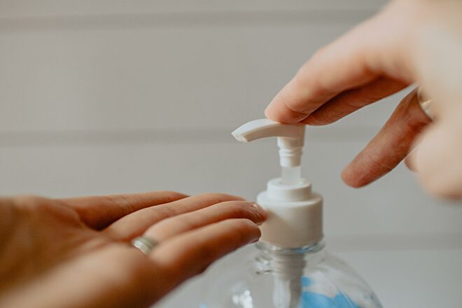 A woman is applying hand gel.